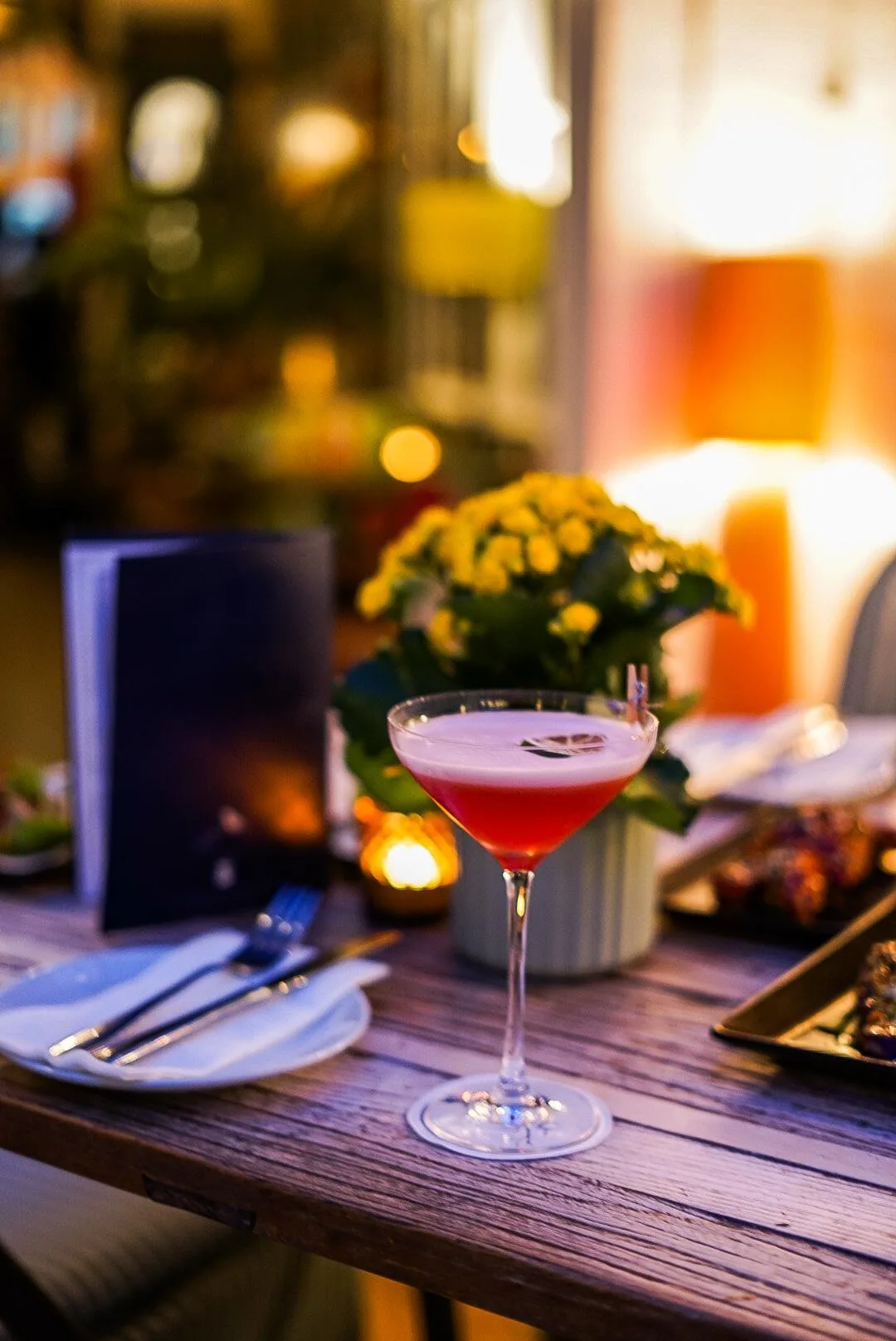 Lychee martini in a martini glass on a candlelit restaurant table