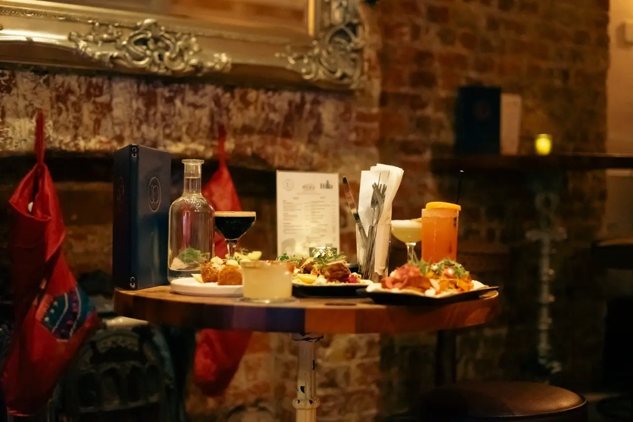 Cosy bar table with sharing plates and cocktails against exposed brick